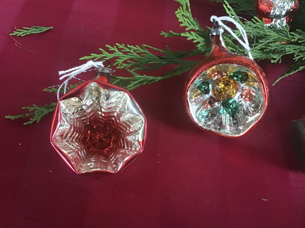 Twee rode kerstballen met een glinsterende binnenkant op een rode doek