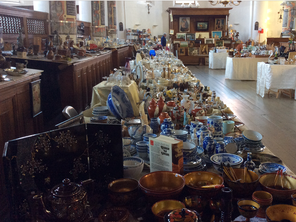 Long table full of blue and white crockery, bowls and black lacquer panels in the Bonifaciuskerk