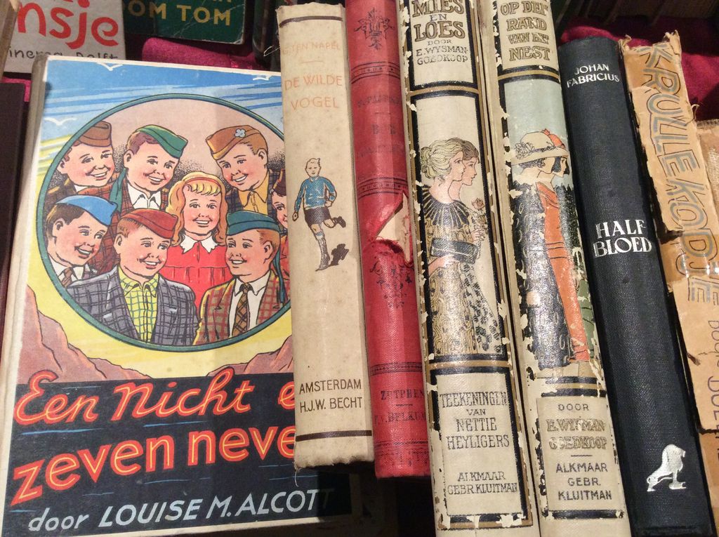 Row of old children's books and bound books with spines and covers in different colours