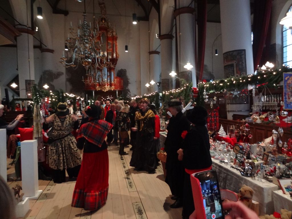 Dickens-figuren zingen in het gangpad tussen de kramen