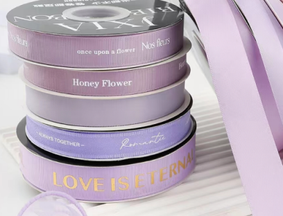 Lavender custom printed satin ribbon rolls with gold and white logos