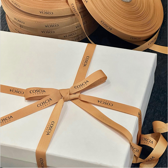 White gift box tied with warm amber custom COSCIA grosgrain ribbon