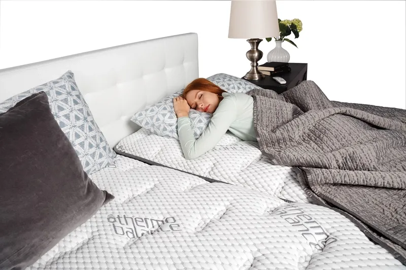 A beautiful woman with red hair sleeping on a new mattress.