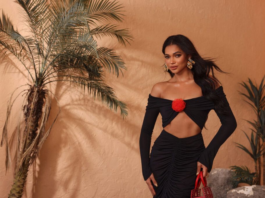 A woman posing next to a plant