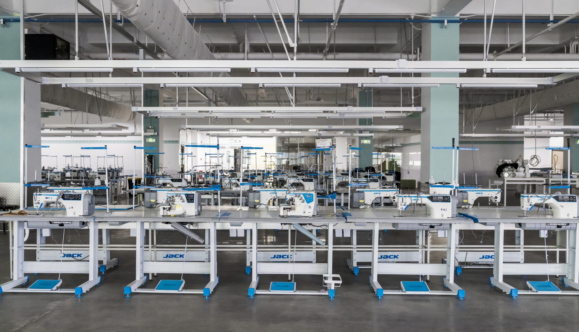 Rows of industrial sewing machines in a clean, modern factory setting