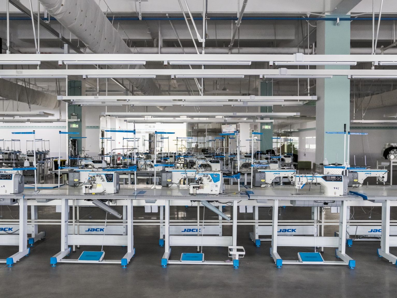 Rows of industrial sewing machines in a clean, modern factory setting