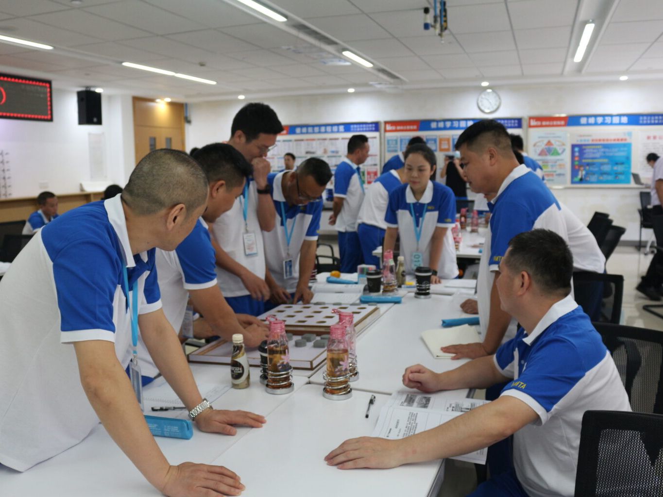 A group of people in blue and white uniforms collaborating around a table