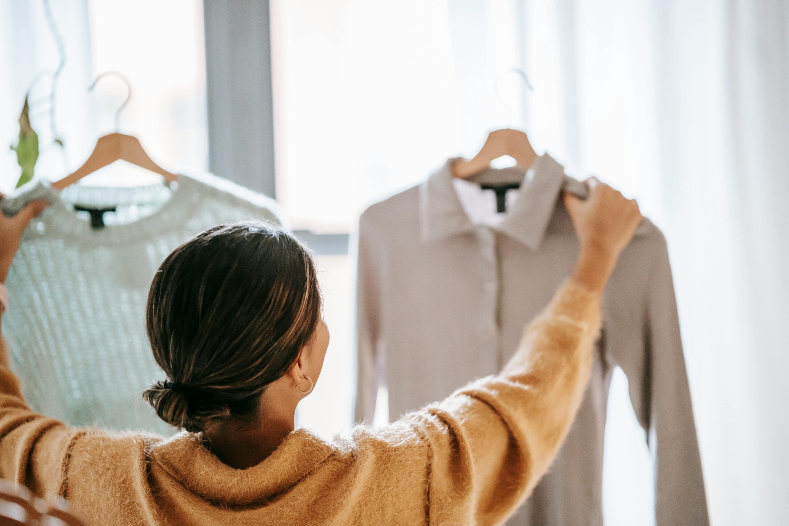 A woman holding up two clothing items