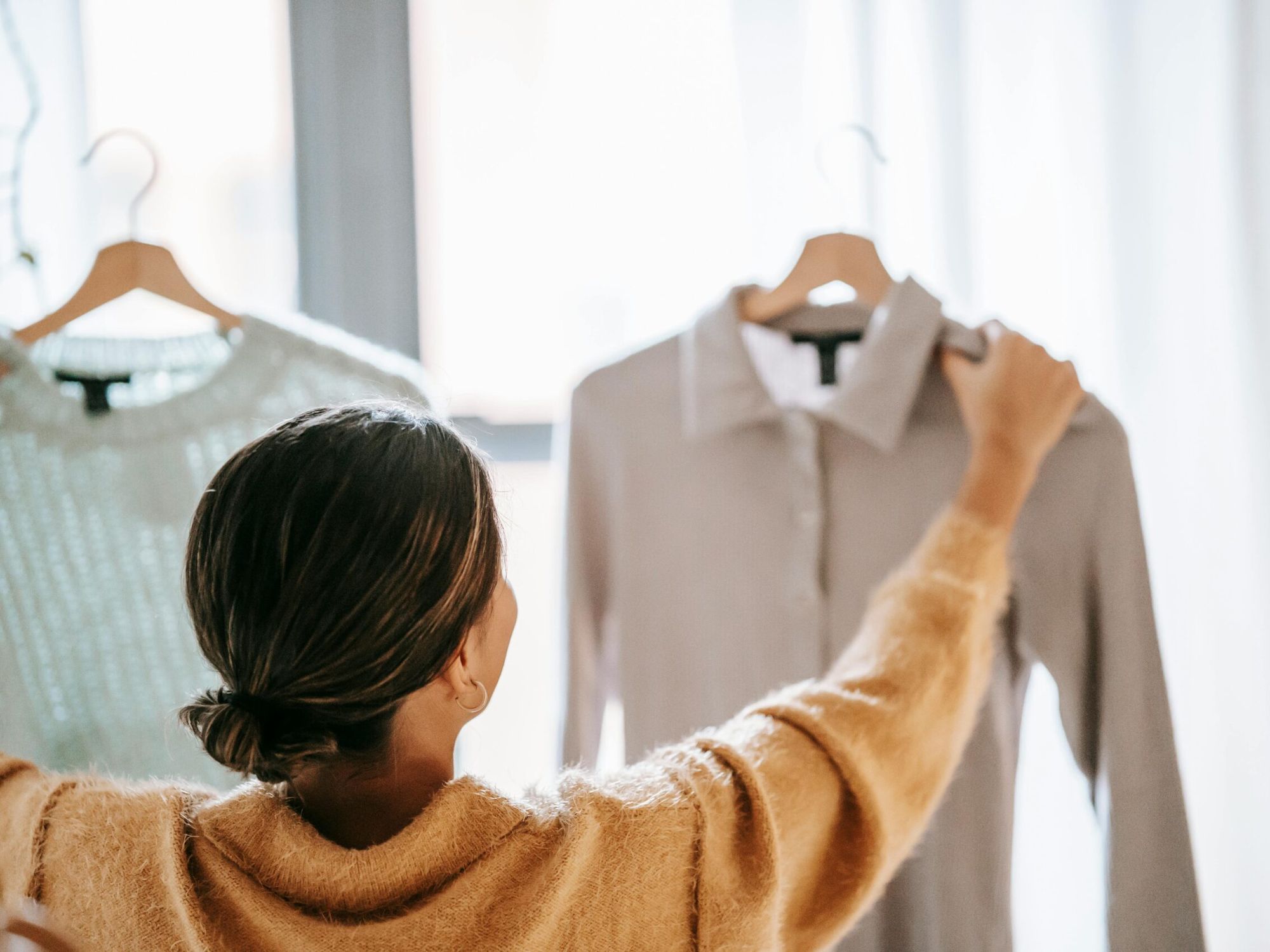 A woman holding up two clothing items