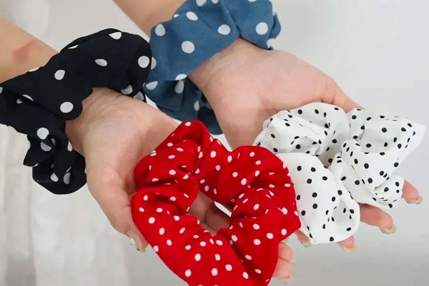 Hands holding and wearing polka dot scrunchies