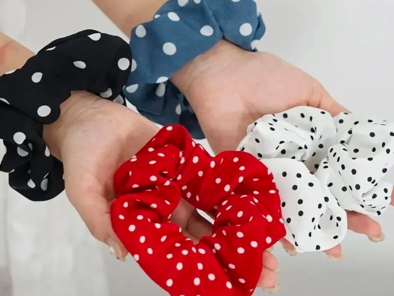 Hands holding and wearing polka dot scrunchies
