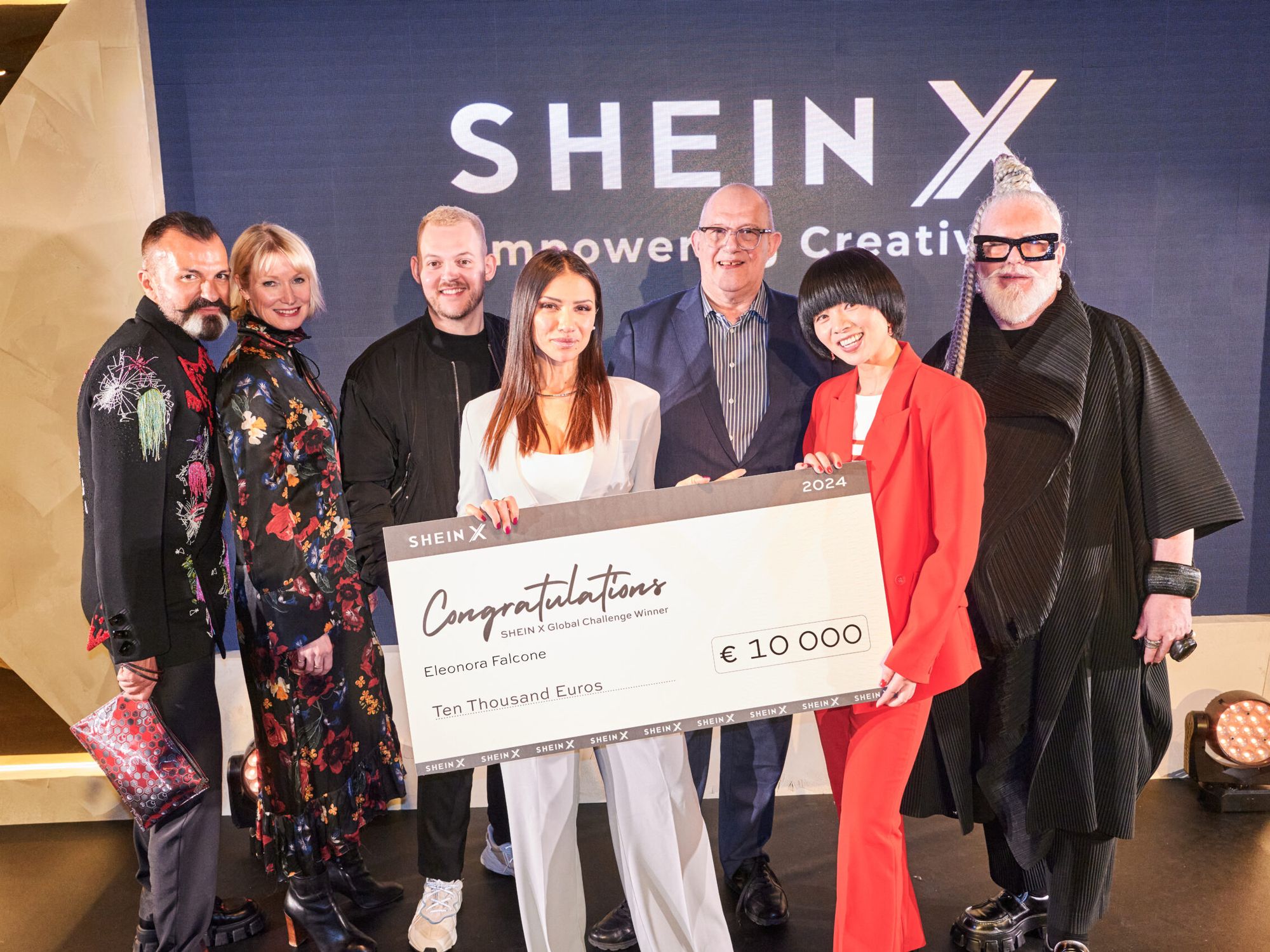A group of people are standing on stage at the SHEIN X event