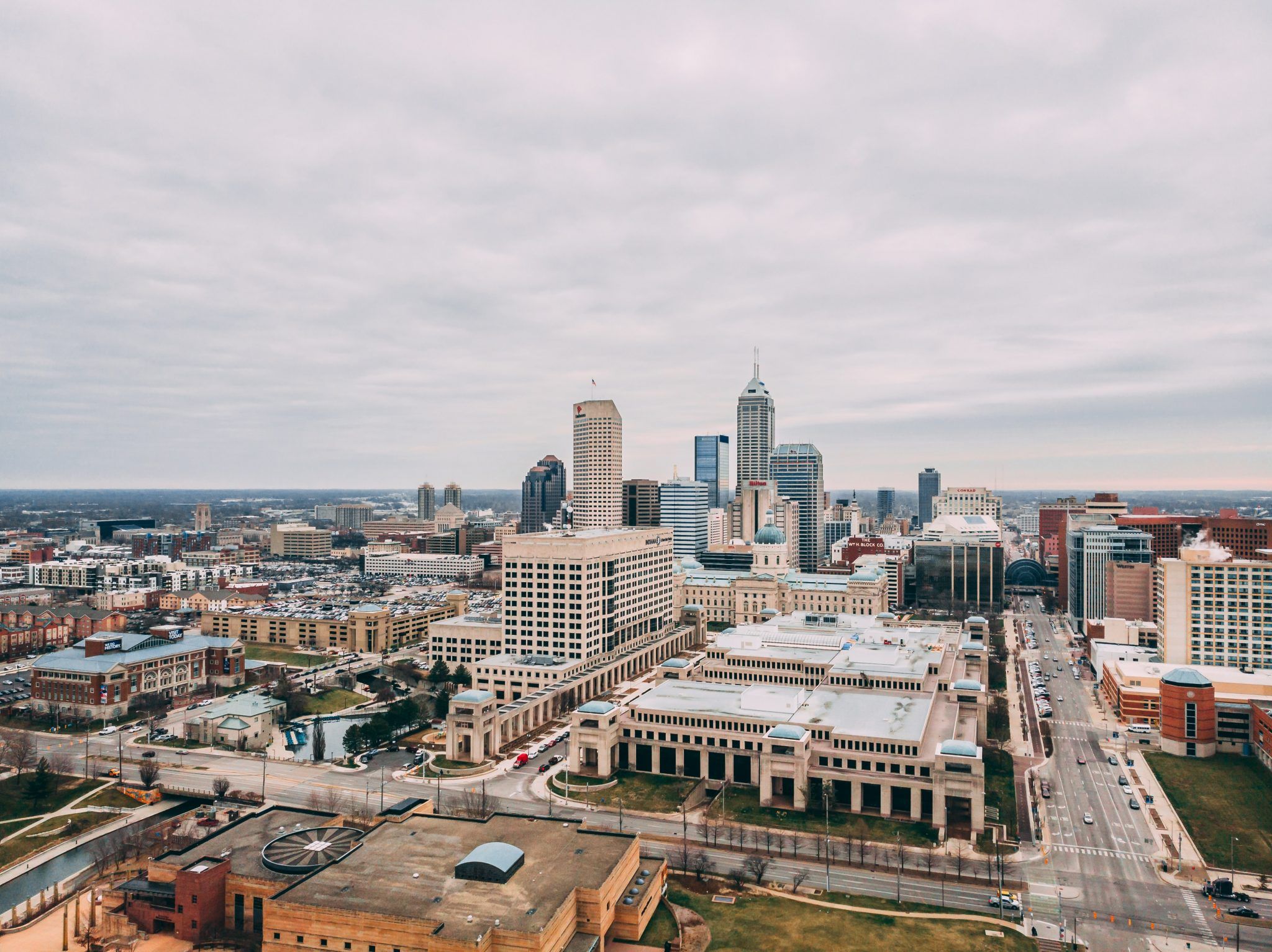 A cityscape featuring tall buildings, streets, and a mix of modern and older architecture under a cloudy sky