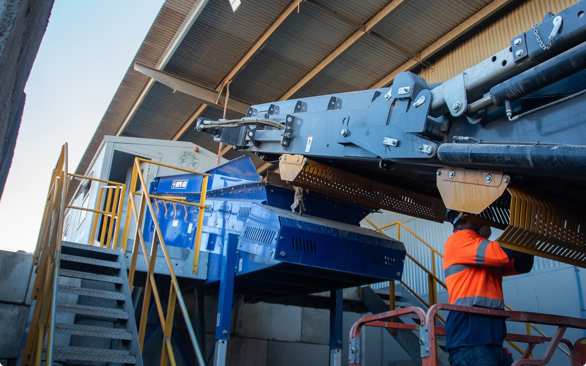 Technician working on an overhead conveyor at a recycling plant