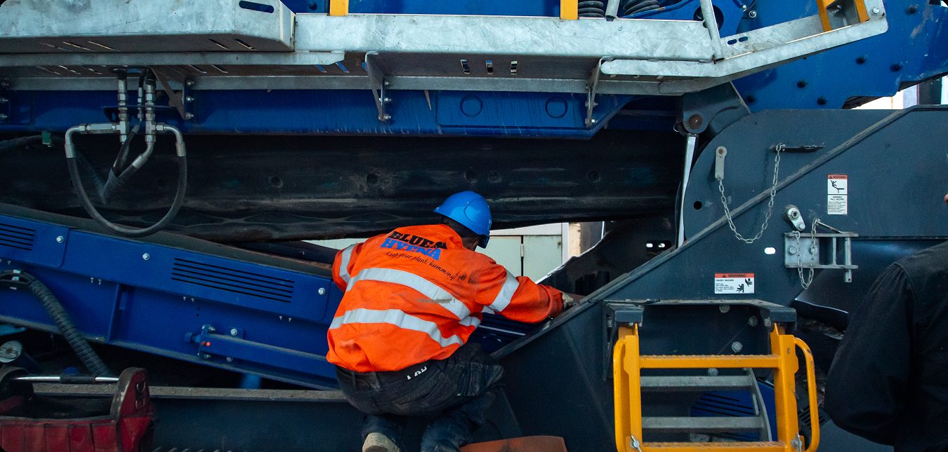 Technician inspecting the underside of a fixed plant conveyor