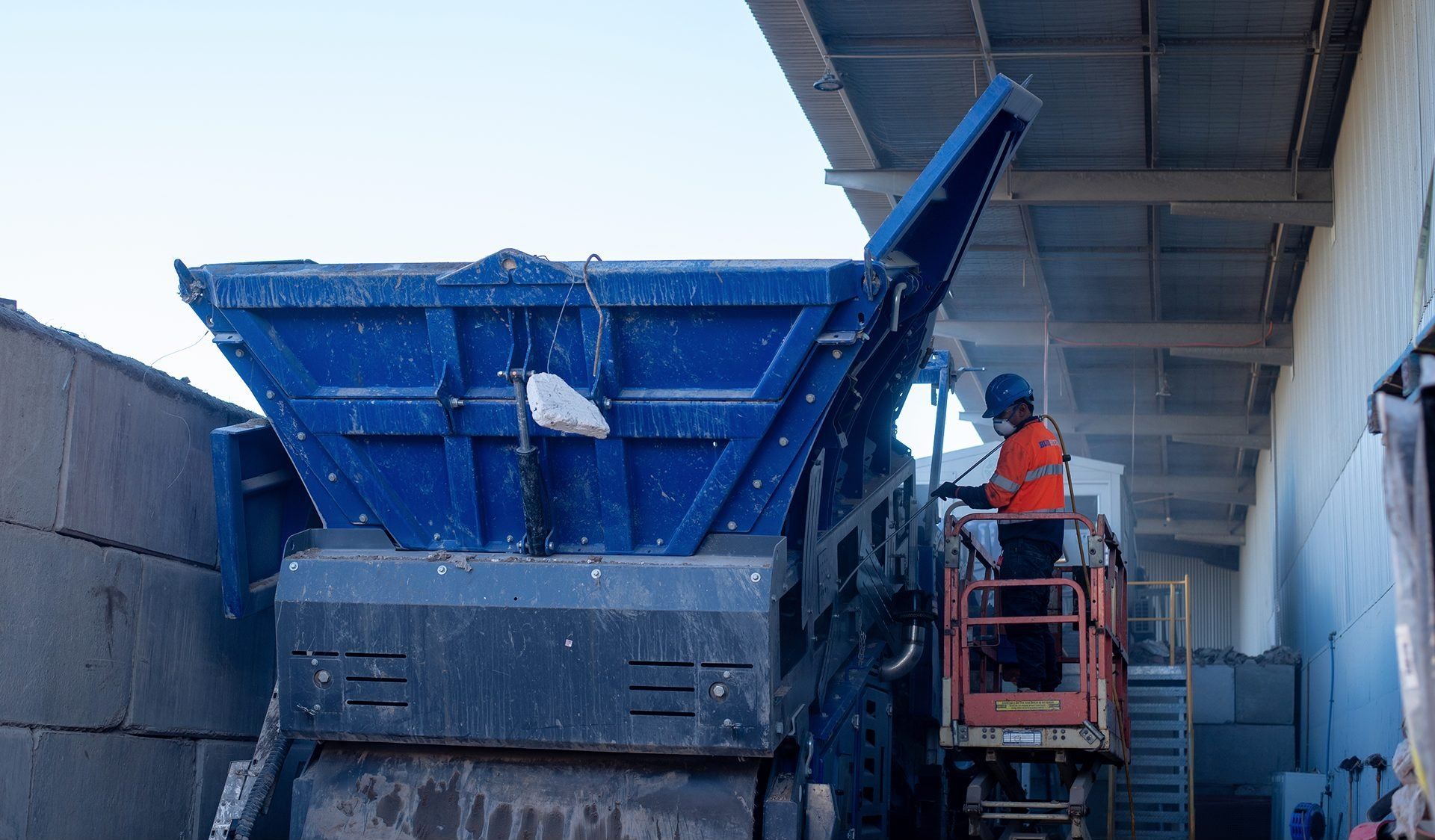 Blue Hyena technician working from an elevated platform beside a conveyor