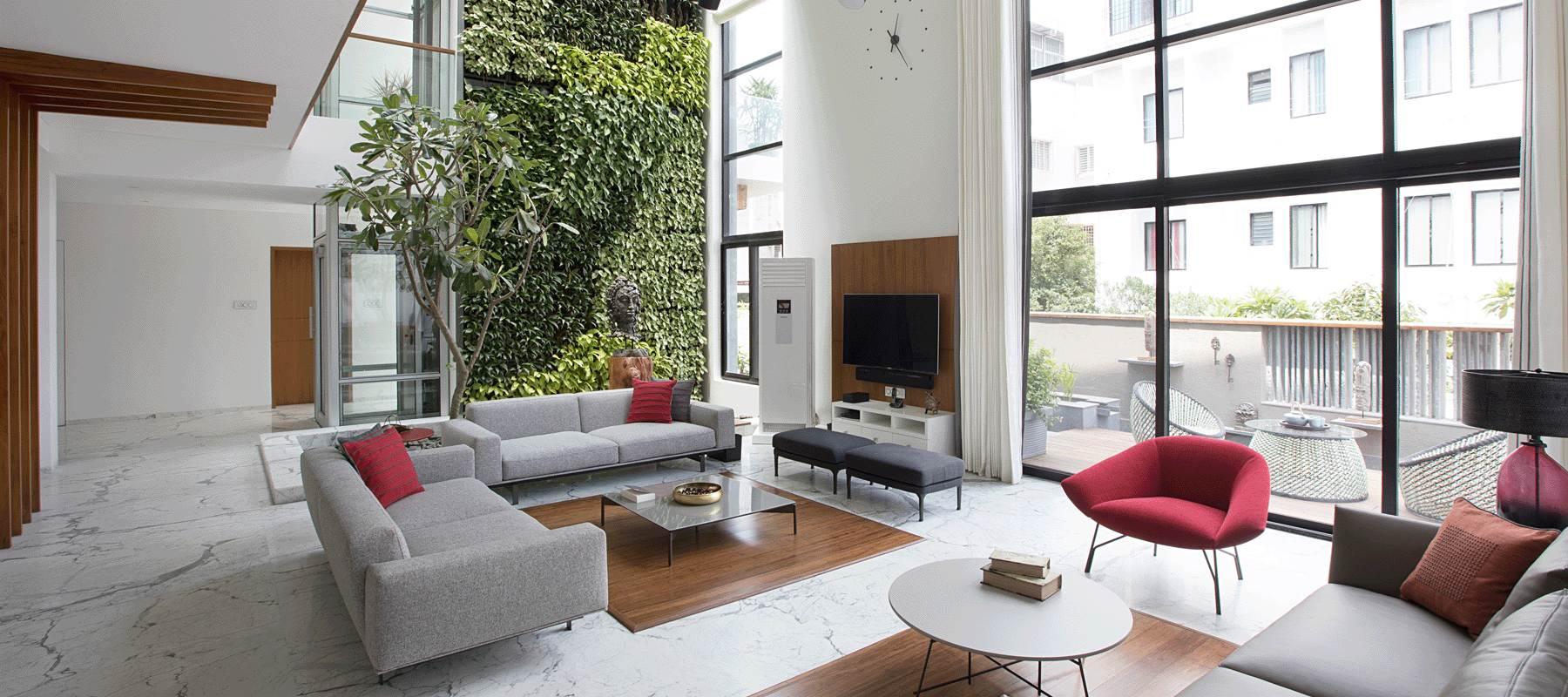 House of Lines, Satara: double-height living room with a planted green wall, marble floor, and grey seating