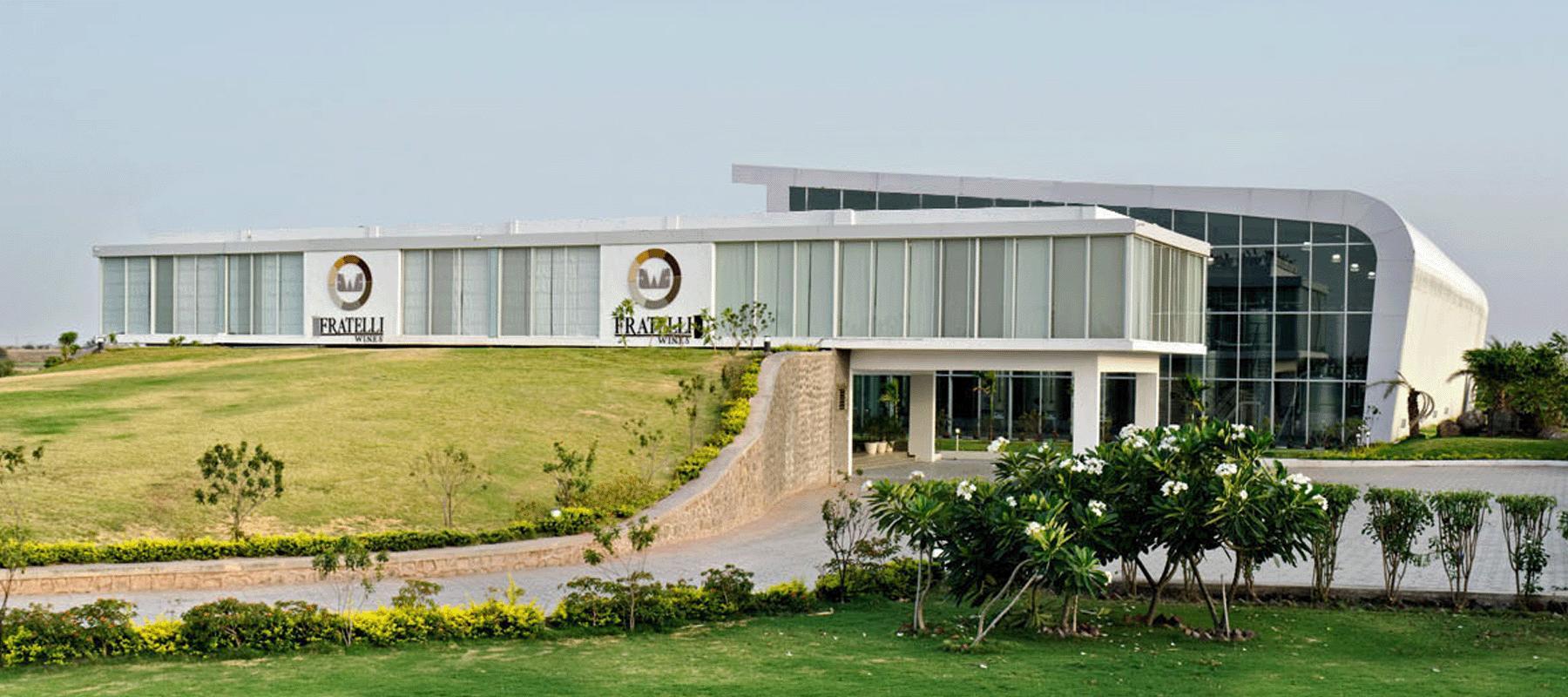 Fratelli Wines winery at Akluj: long glazed hall with a sweeping white roof above landscaped grounds
