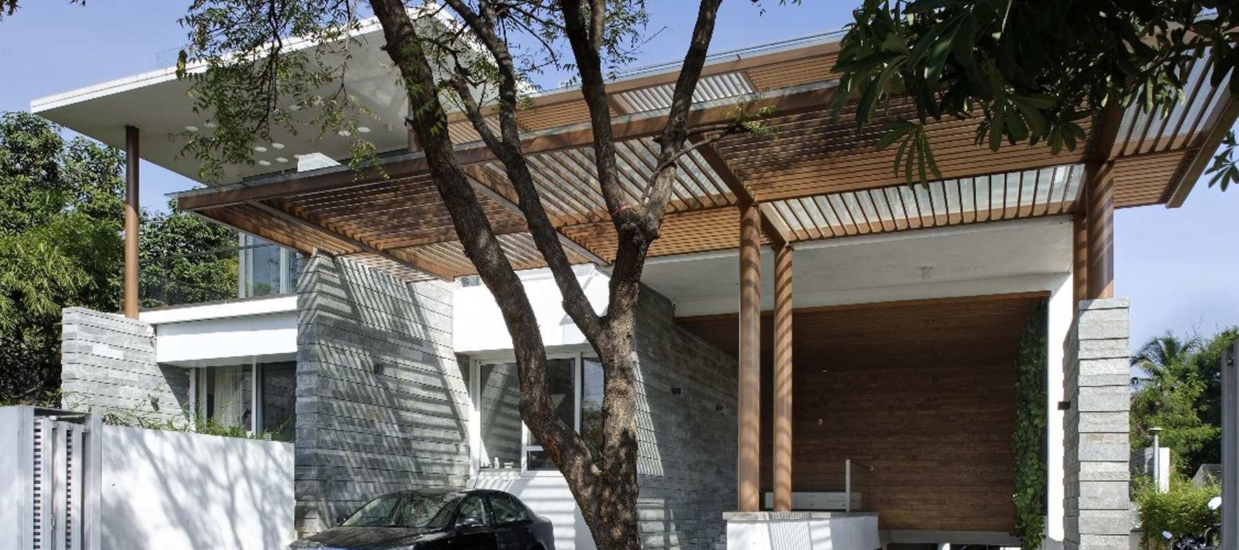 Fusion House, Pune: stone-clad residence with a broad timber pergola sheltering the entrance court