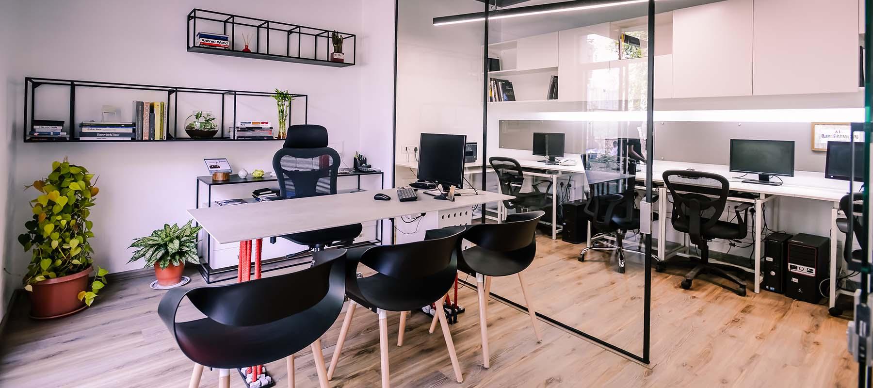 Shared studio workspace with desks, books and a glass meeting room