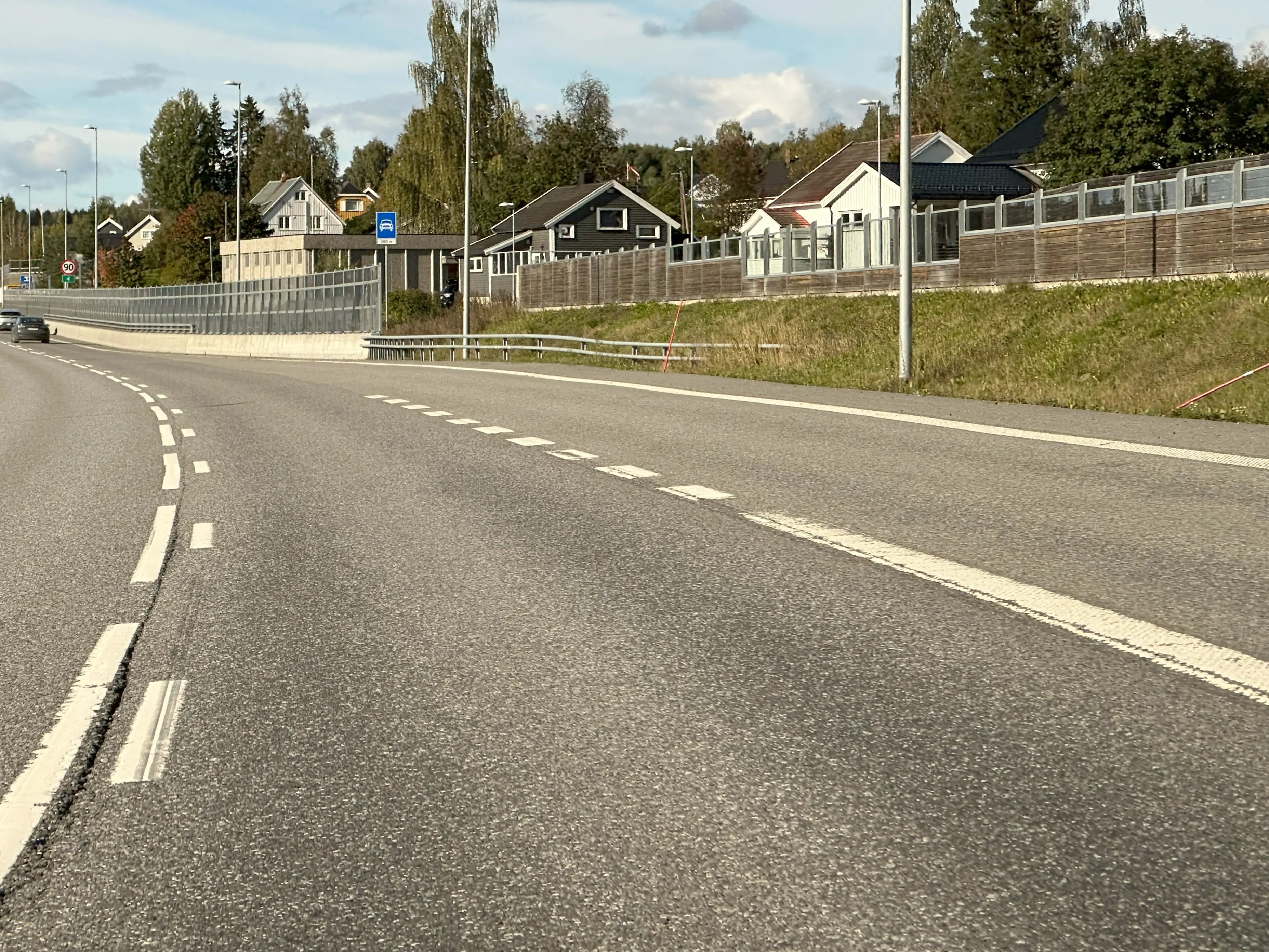 Fartsøkningsfelt til motorvei med småhusbebyggelse i bakgrunnen.