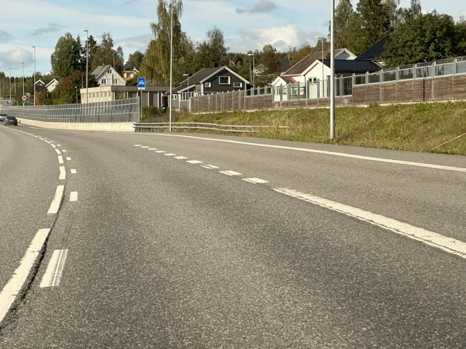 Fartsøkningsfelt til motorvei med småhusbebyggelse i bakgrunnen.