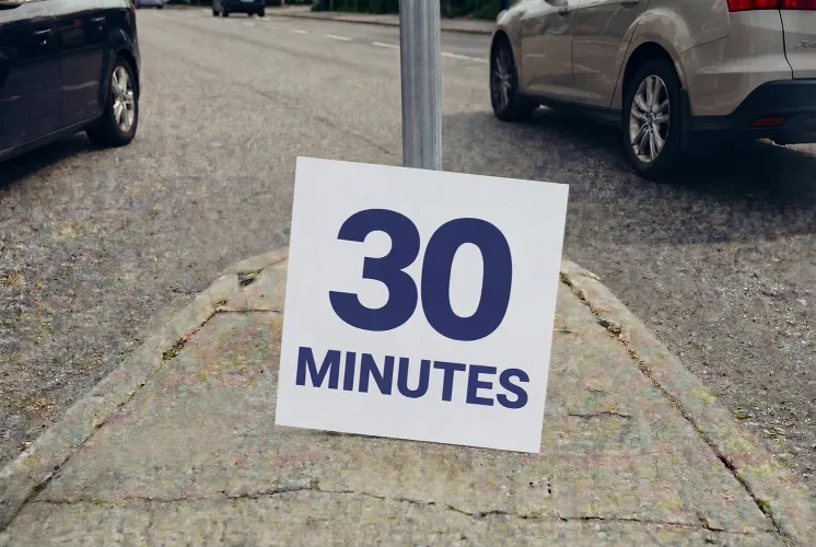 A sign with the text “30 minutes” in a median strip, with cars on both sides.