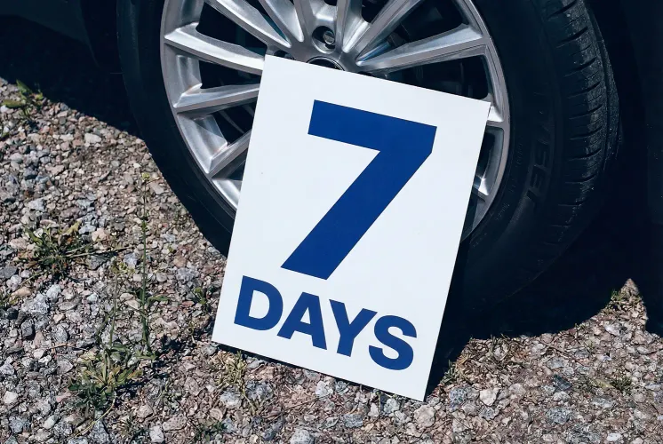 A sign with the text ‘7 days’ leans against a wheel.