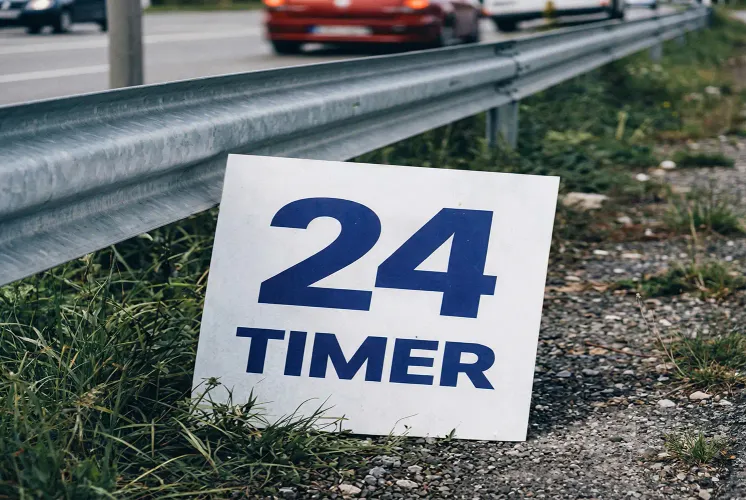 Et skilt med teksten '24 timer' lener seg på et autovern.