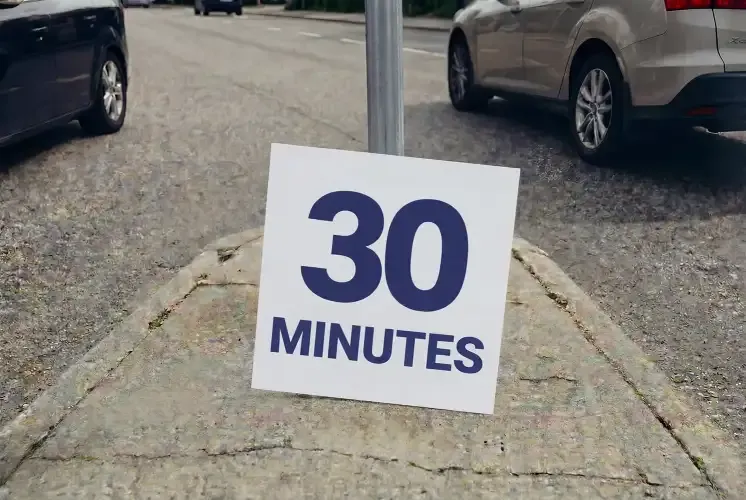 A sign with the text “30 minutes” in a median strip, with cars on both sides.