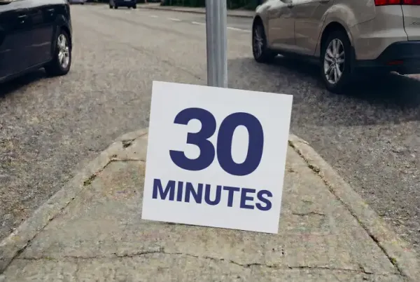 A sign with the text “30 minutes” in a median strip, with cars on both sides.