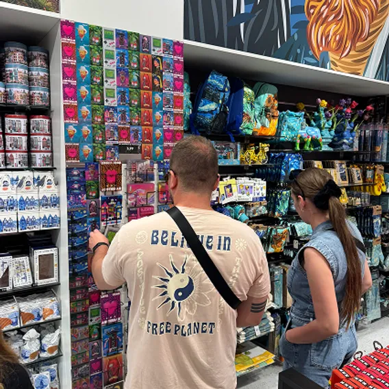 Visitors browsing an Orange Panda postcard wall in a souvenir shop