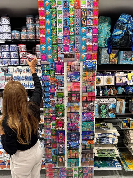 Shopper reaching for a 3D postcard on a tall Orange Panda display in a souvenir shop