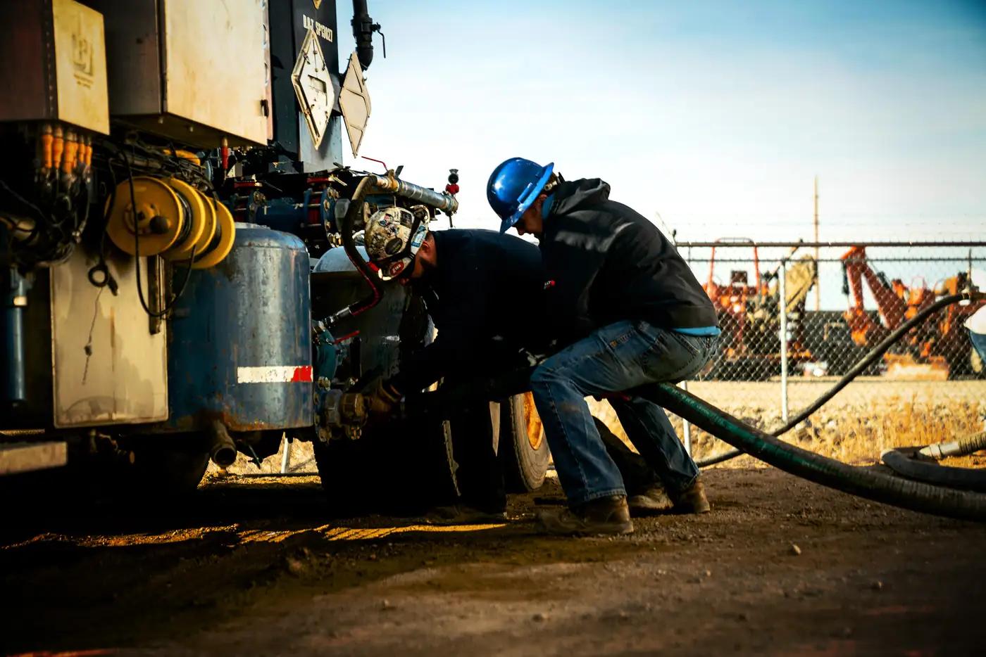 Two OneCor crew members connecting pump hoses on location