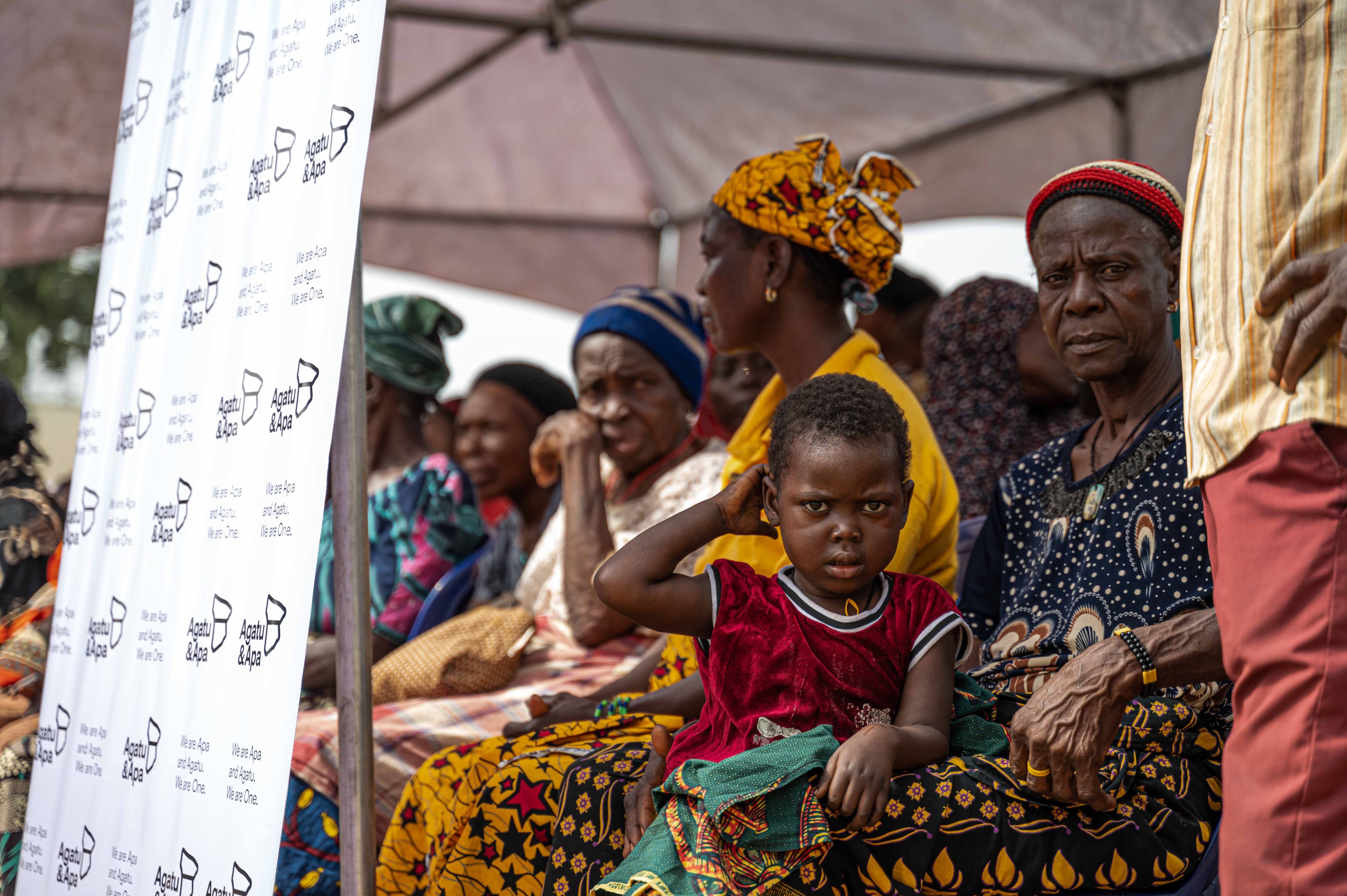 A group of women and children seated under the outreach tent in Usha, reflecting the community’s turnout and the need for accessible, compassionate healthcare.