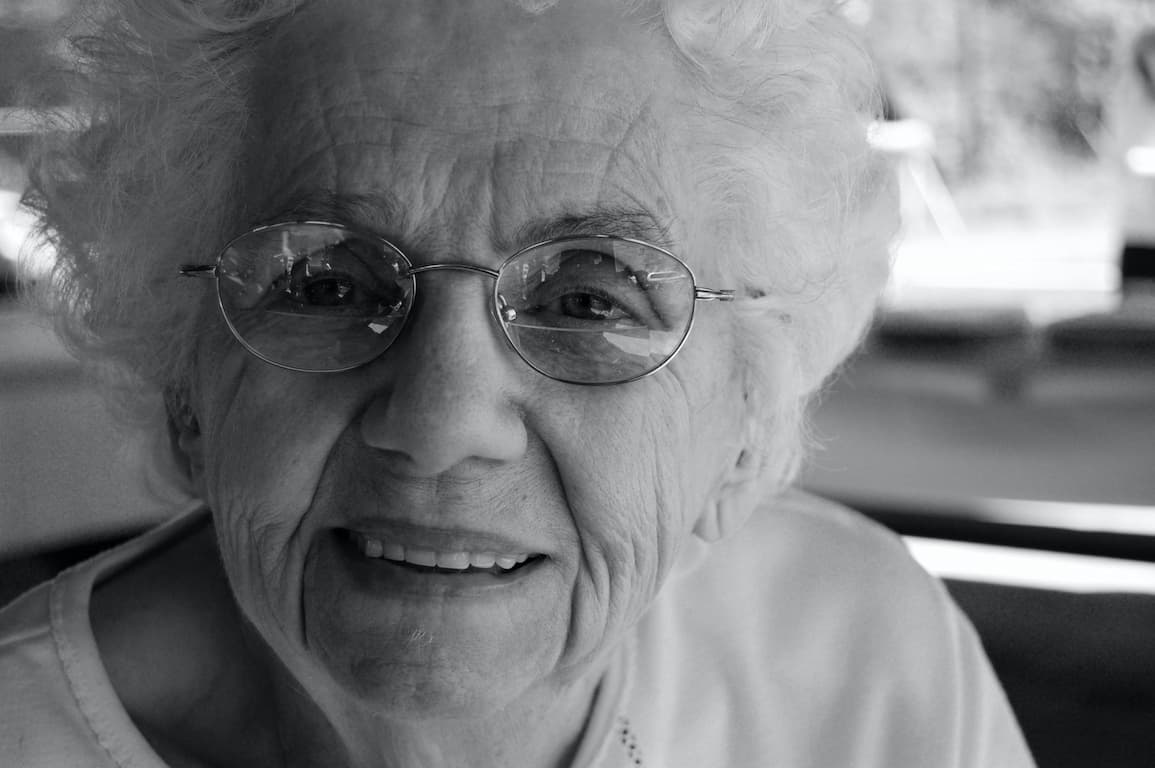 A black and white picture of an old lady smiling.