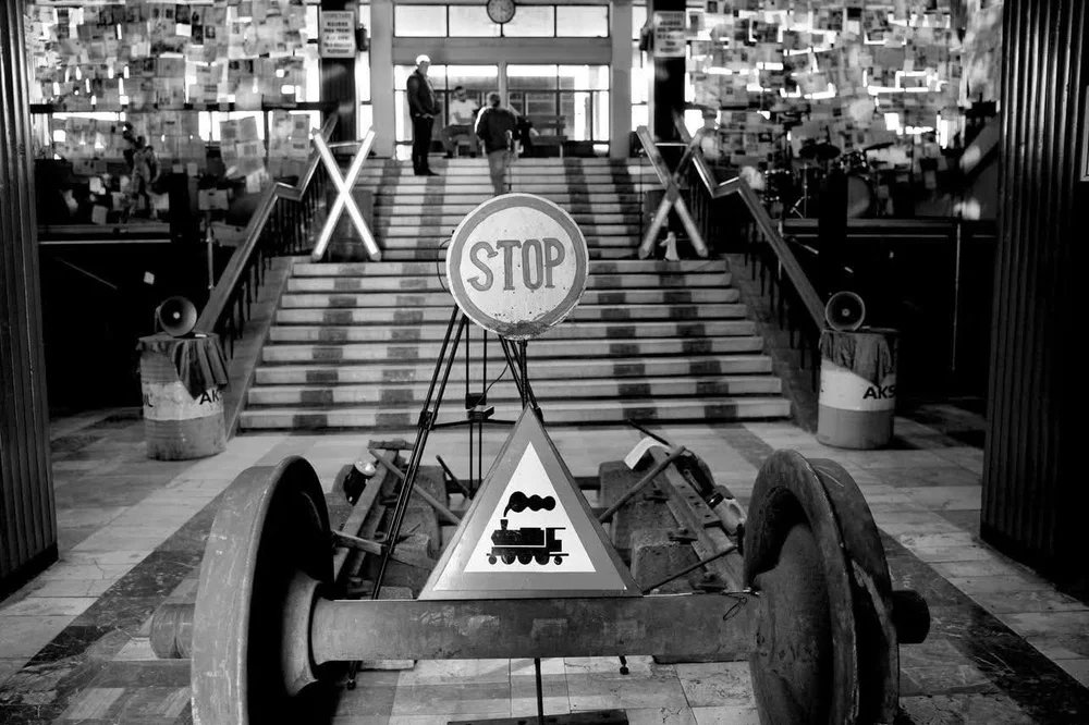 A disused railway terminal interior, with a stop sign and an old locomotive wheel