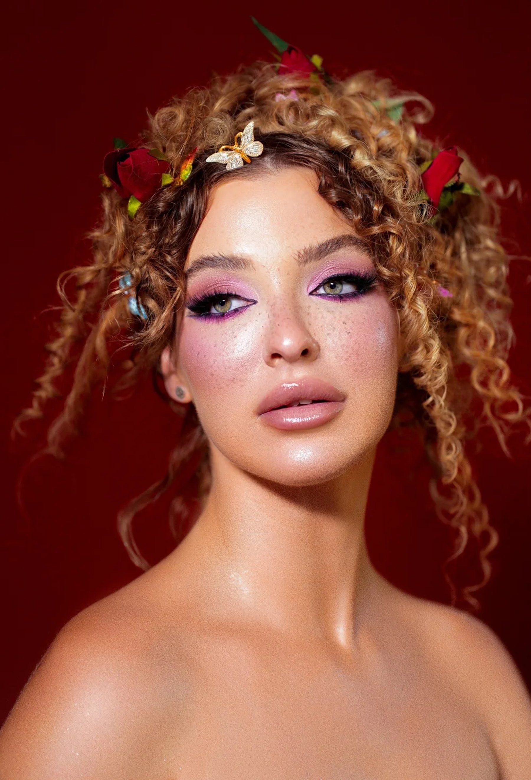 Beauty portrait with floral styling against a deep red background — photograph by Ergys Shehu.