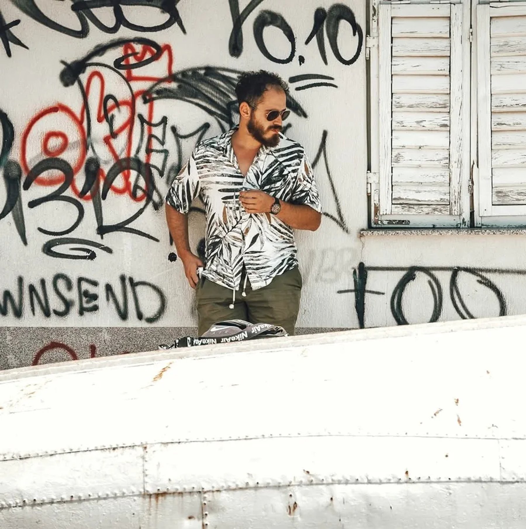 Ergys Shehu in a patterned shirt against a graffiti-covered wall, photo 3
