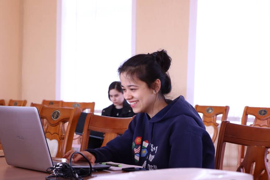 A college student smiles at her laptop screen.