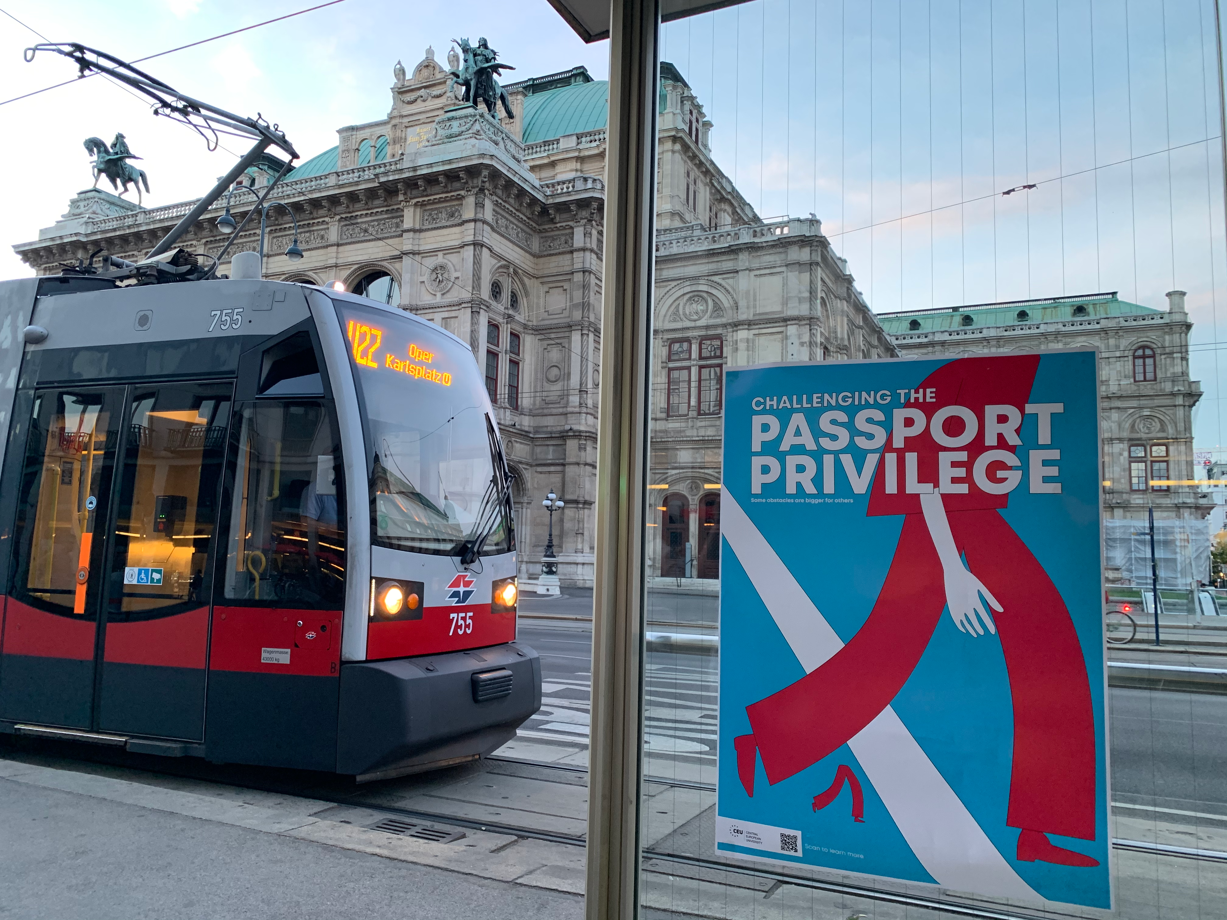 Blue “Challenging the Passport Privilege” poster hung in front of a tram.
