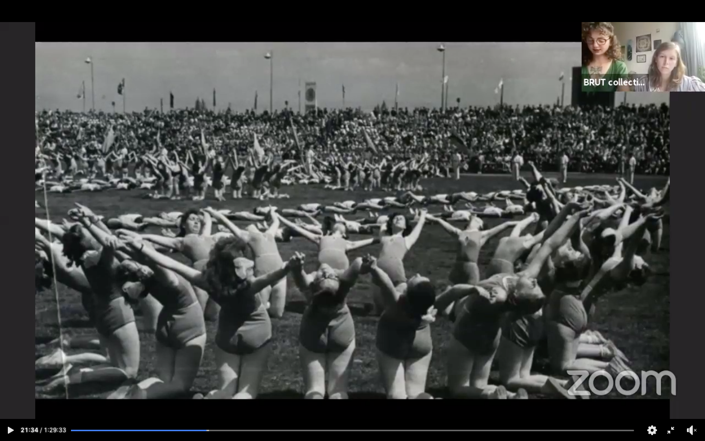 A football field of women in leotards, holding hands in large circles and leaning back; others lay in lines on the ground