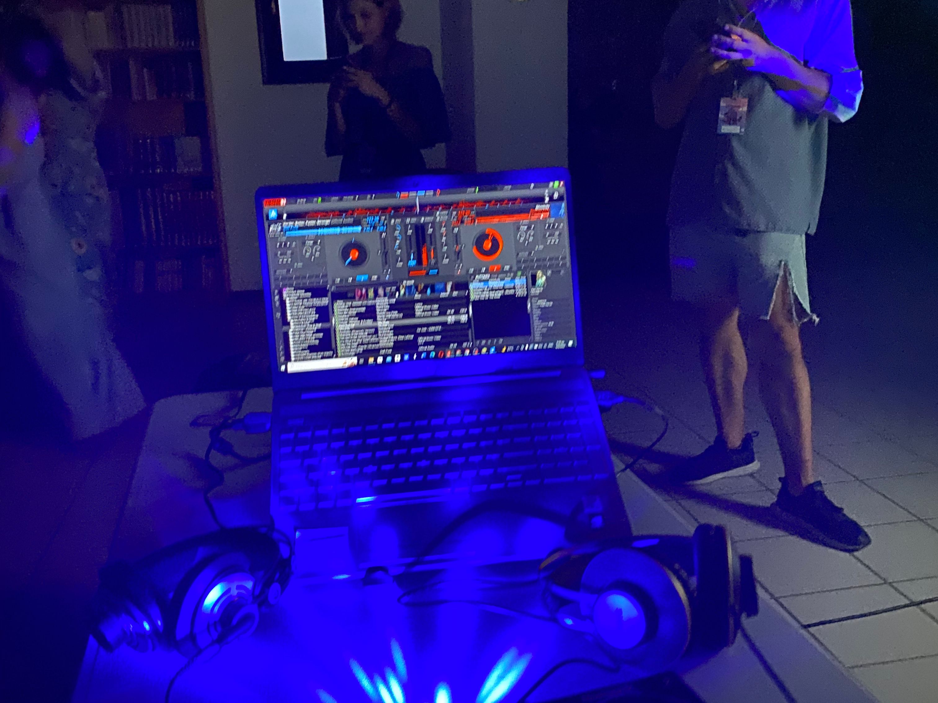 A lit-up DJ setup in a dark room with people in the background