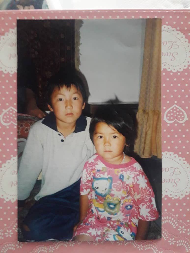 A brother and sister, maybe 8 and 4 years old, in a home. The photo is in a pink and white frame.