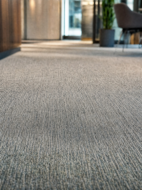 A clean, stain-free carpet in a bright modern office hallway, after cleaning.