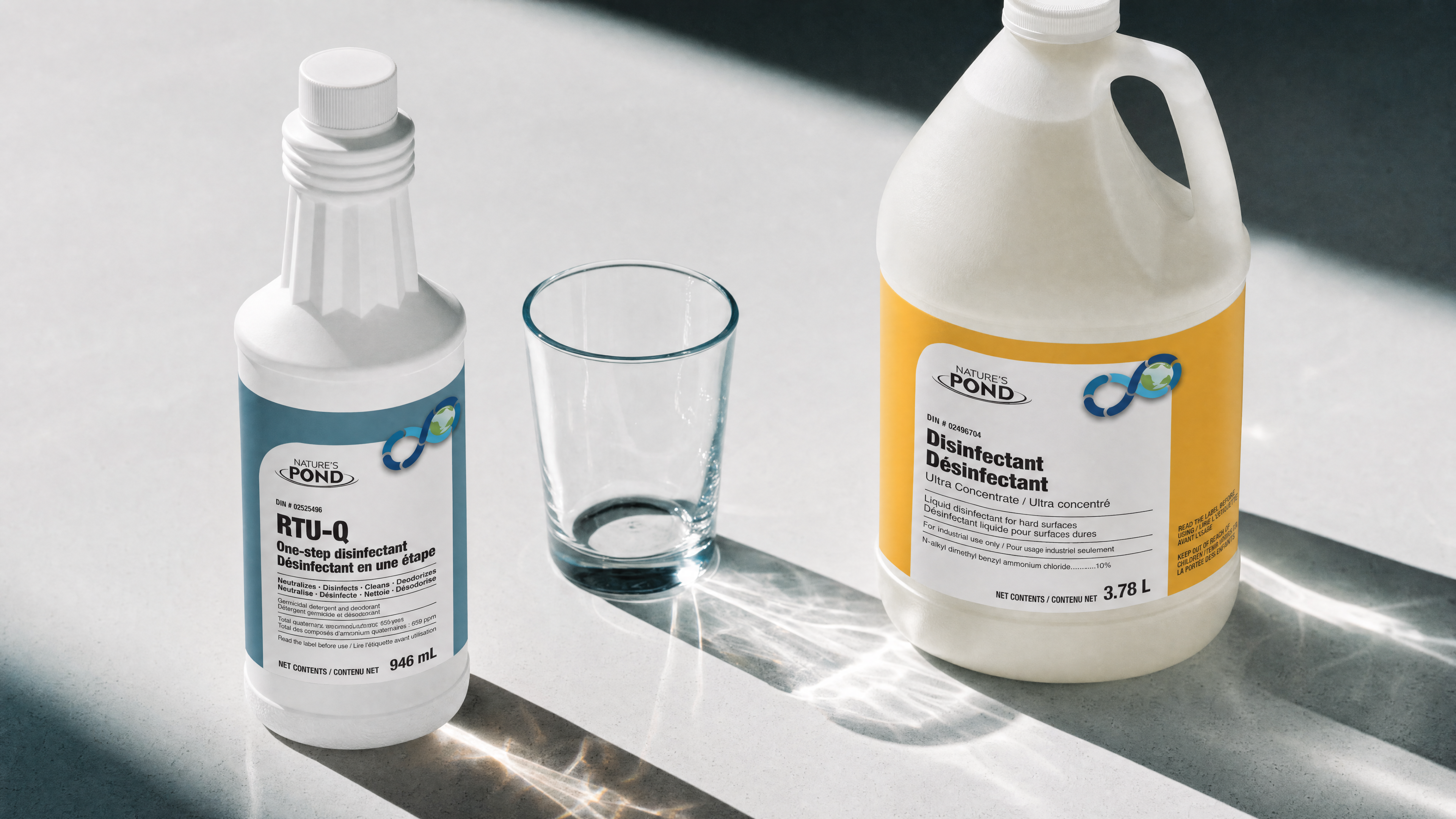 A small concentrate bottle beside a much larger ready-to-use spray bottle on a sunlit counter, showing the size difference.