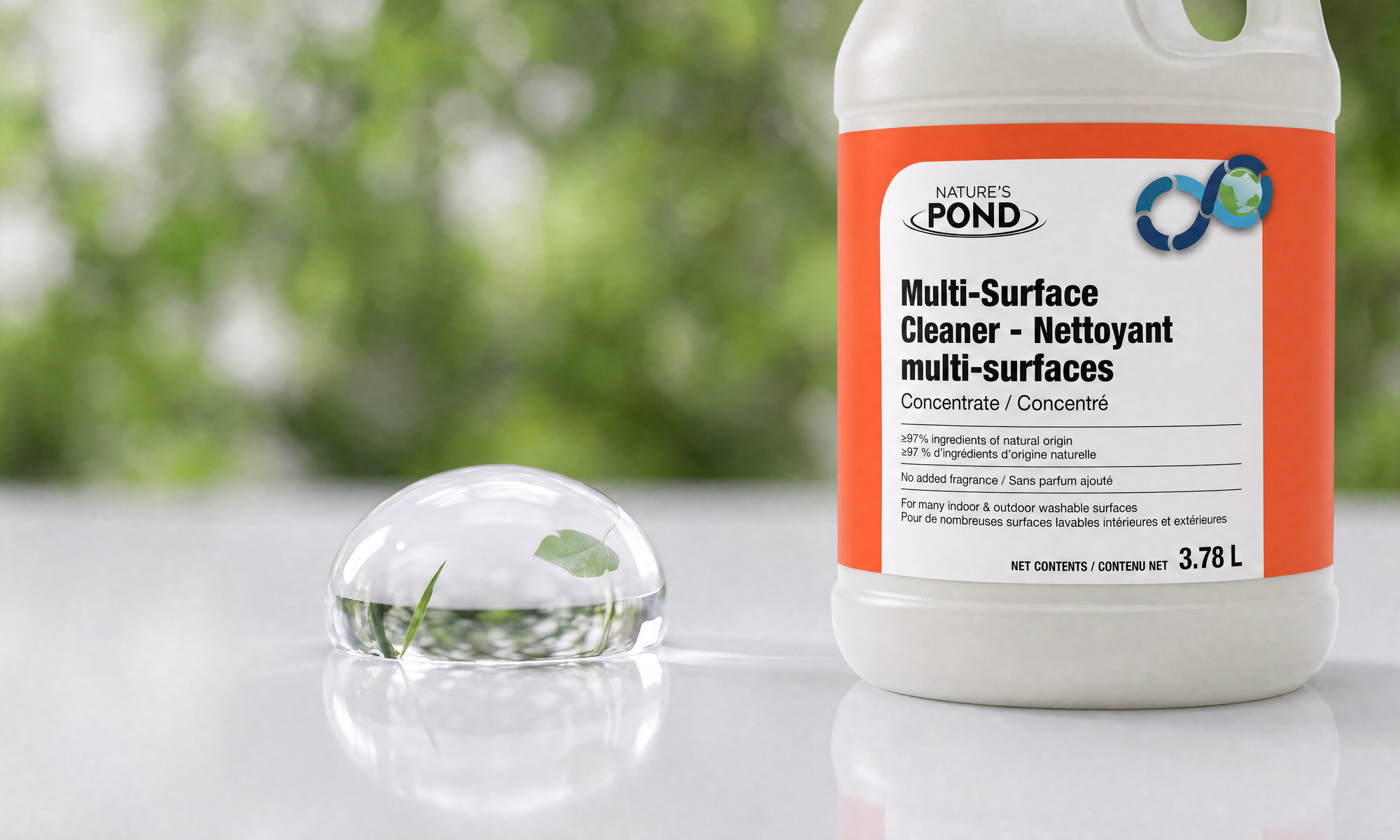 A water droplet holding a green leaf beside a Nature’s Pond Multi-Surface Cleaner bottle