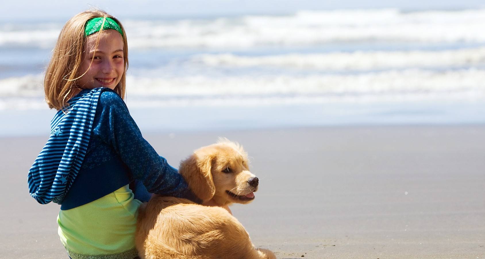 Little girl with her dog on the beach