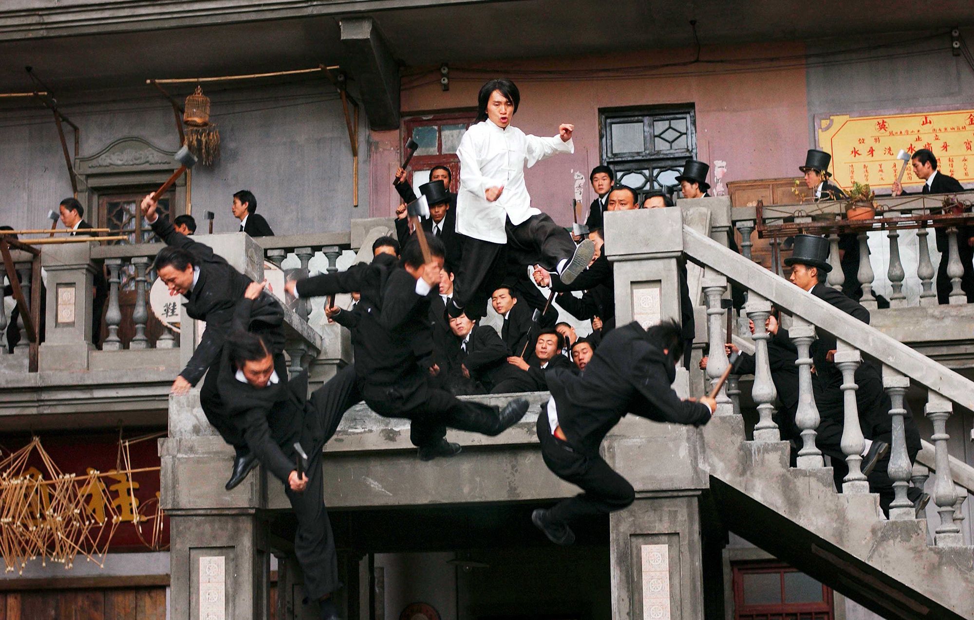 A man dressing in white fights with many men in suit on a staircase