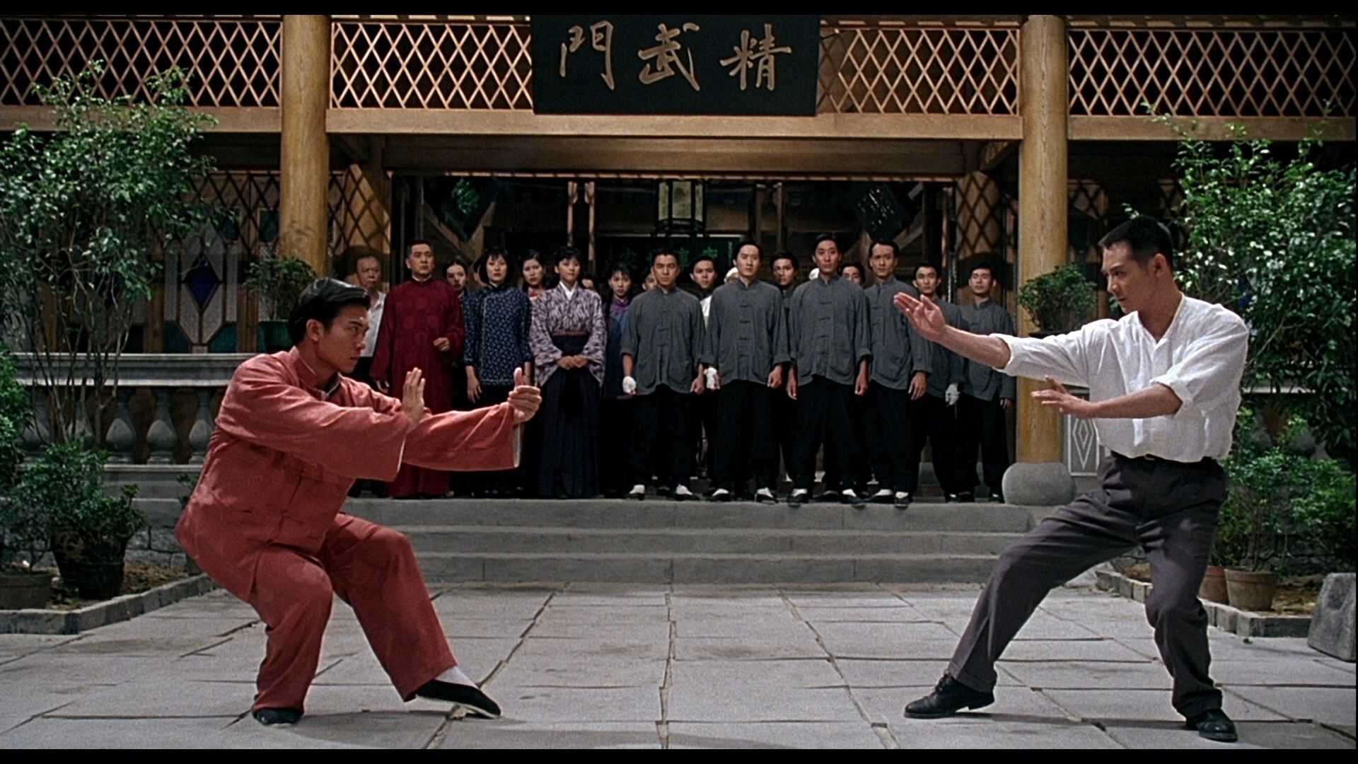 2 men fighting martial arts with more people watching